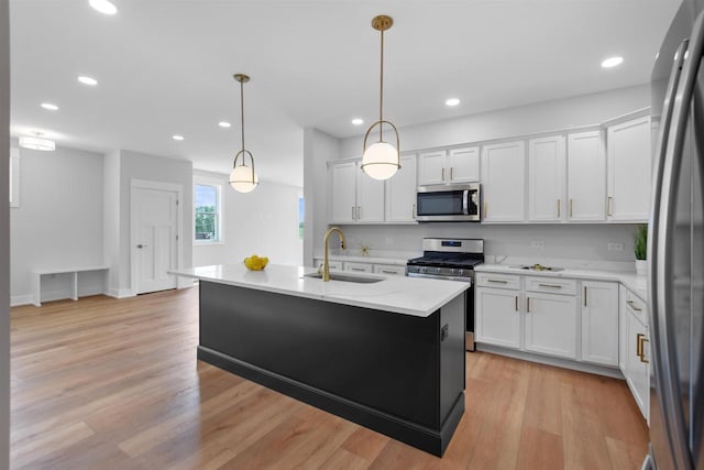 kitchen featuring white cabinetry, sink, stainless steel appliances, and a center island with sink