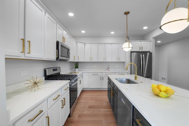 kitchen featuring white cabinets, decorative light fixtures, sink, and appliances with stainless steel finishes