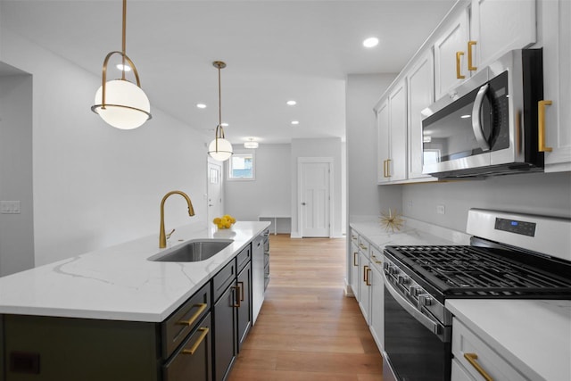 kitchen featuring sink, pendant lighting, a kitchen island with sink, white cabinets, and appliances with stainless steel finishes