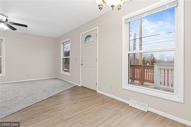 entrance foyer featuring ceiling fan with notable chandelier, a healthy amount of sunlight, and light wood-type flooring