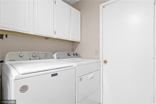 clothes washing area featuring washer and dryer and cabinets