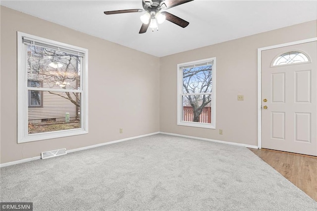 entrance foyer with ceiling fan and light carpet