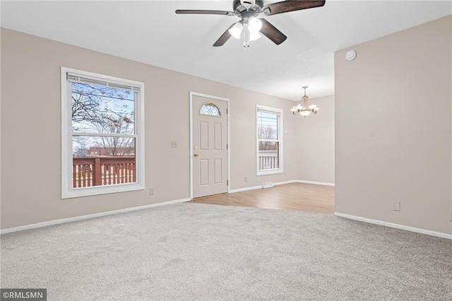 foyer with light carpet and ceiling fan with notable chandelier