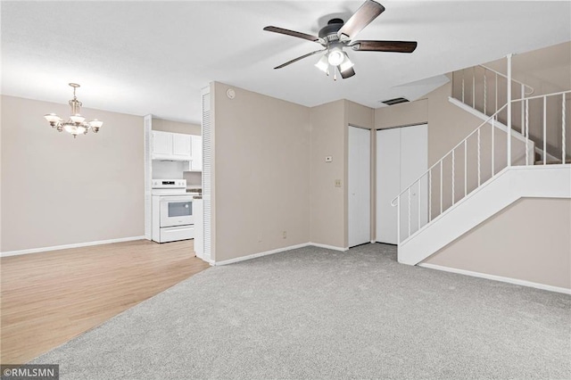 unfurnished living room featuring light carpet and ceiling fan with notable chandelier