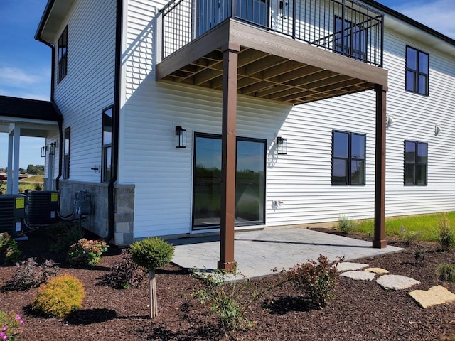 rear view of property with a patio area, a balcony, and central AC unit