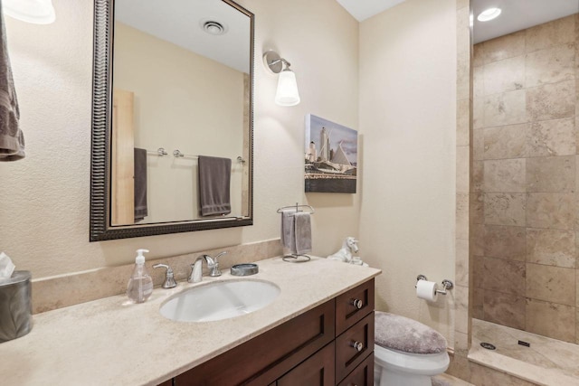 bathroom featuring vanity, toilet, and tiled shower