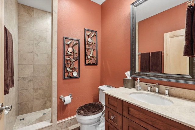 bathroom featuring vanity, toilet, and a tile shower