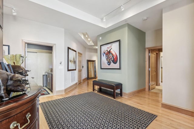 hallway with light hardwood / wood-style floors and track lighting