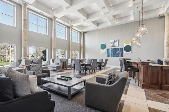 living room with light tile patterned floors, a towering ceiling, and ornate columns