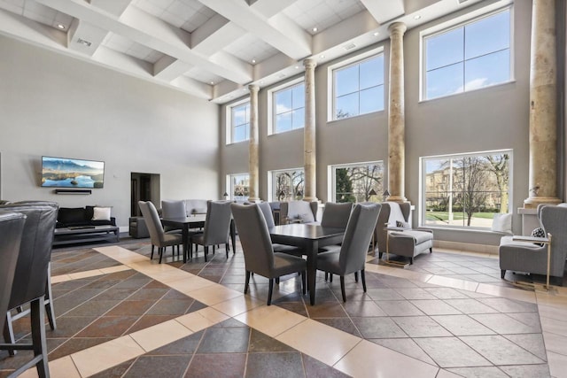 dining room featuring tile patterned floors, a towering ceiling, ornate columns, and beam ceiling