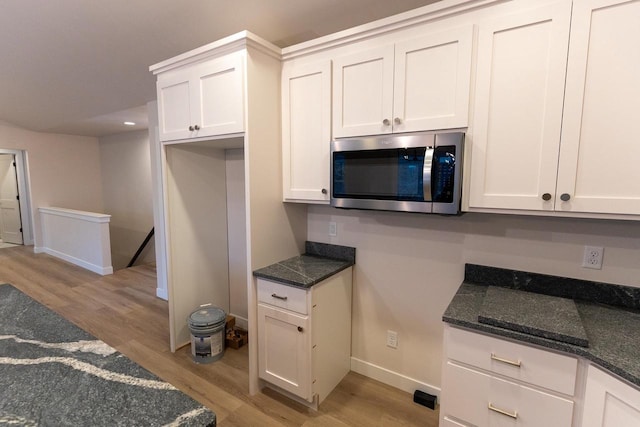 kitchen with dark stone countertops, white cabinetry, and light wood-type flooring