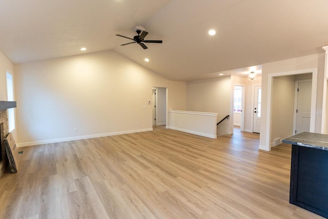 unfurnished living room featuring ceiling fan, light hardwood / wood-style floors, lofted ceiling, and a fireplace