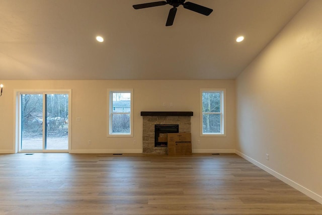 unfurnished living room with ceiling fan, a fireplace, lofted ceiling, and light hardwood / wood-style flooring