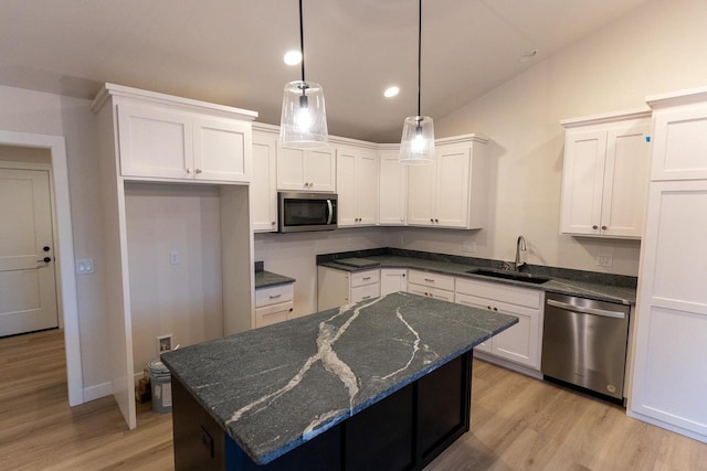 kitchen with sink, a kitchen island, vaulted ceiling, white cabinets, and appliances with stainless steel finishes