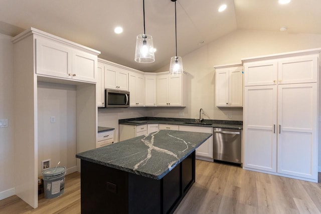 kitchen with stainless steel appliances, sink, a center island, white cabinetry, and hanging light fixtures