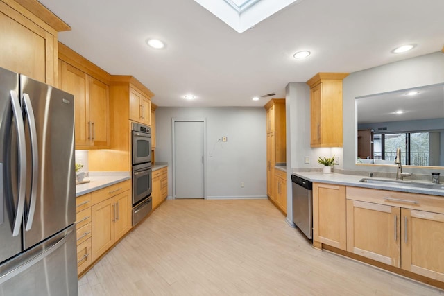 kitchen featuring light brown cabinets, sink, light hardwood / wood-style flooring, a skylight, and appliances with stainless steel finishes