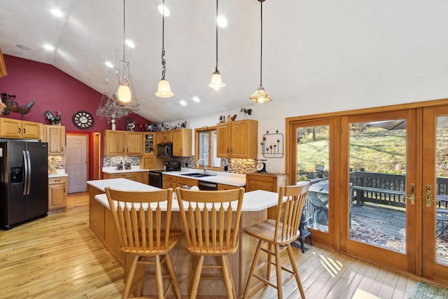 kitchen featuring sink, hanging light fixtures, backsplash, a kitchen island, and black appliances