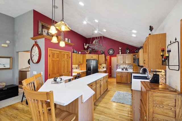 kitchen featuring backsplash, black refrigerator with ice dispenser, a center island, light hardwood / wood-style floors, and hanging light fixtures