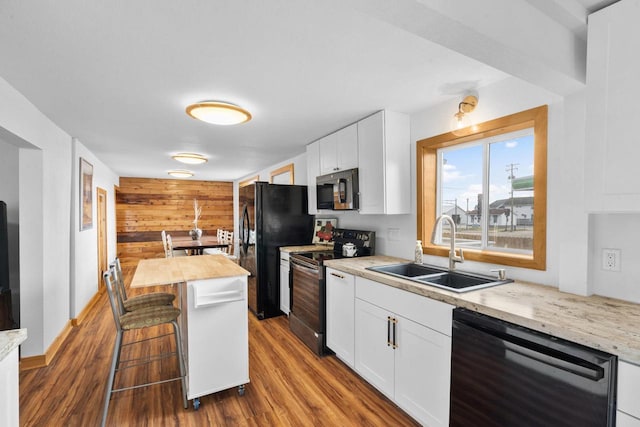 kitchen with white cabinetry, sink, dark hardwood / wood-style flooring, a breakfast bar area, and black appliances