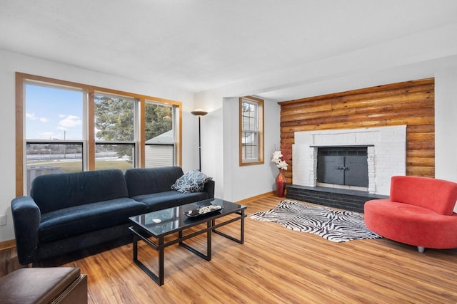 living room with a fireplace, light hardwood / wood-style floors, and rustic walls