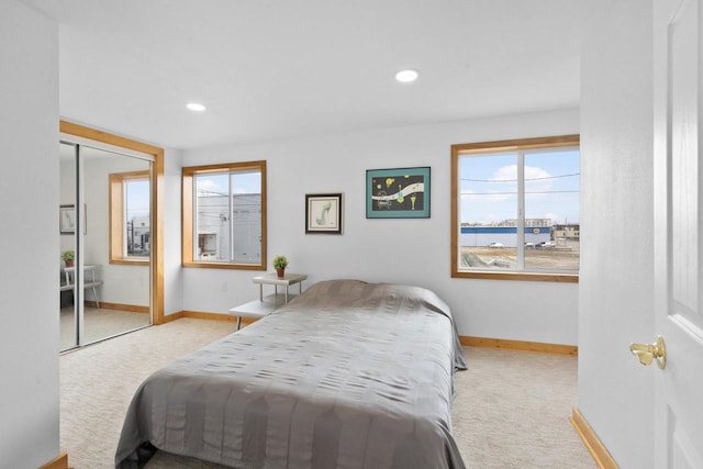 bedroom featuring light colored carpet, a closet, and a water view