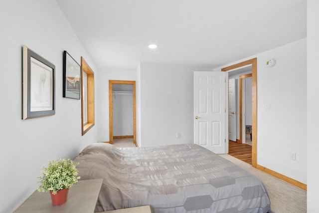 bedroom featuring a walk in closet, light carpet, and a closet