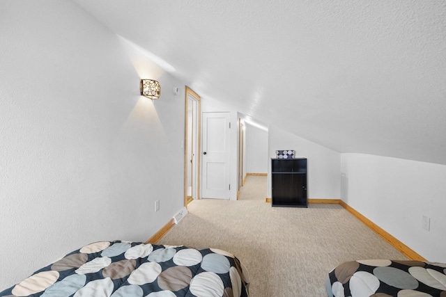 carpeted bedroom featuring lofted ceiling and a textured ceiling