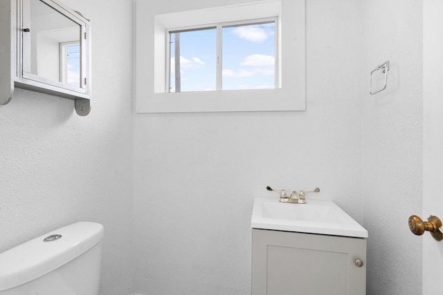 bathroom with vanity, toilet, and a healthy amount of sunlight