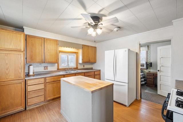 kitchen featuring a center island, light wood-type flooring, white appliances, and sink