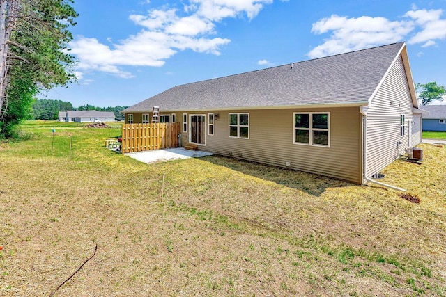 back of house with central AC unit and a lawn