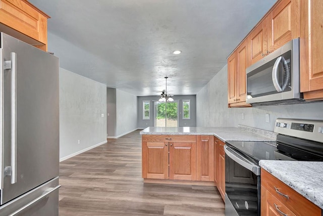 kitchen with ceiling fan, stainless steel appliances, light hardwood / wood-style flooring, kitchen peninsula, and decorative light fixtures