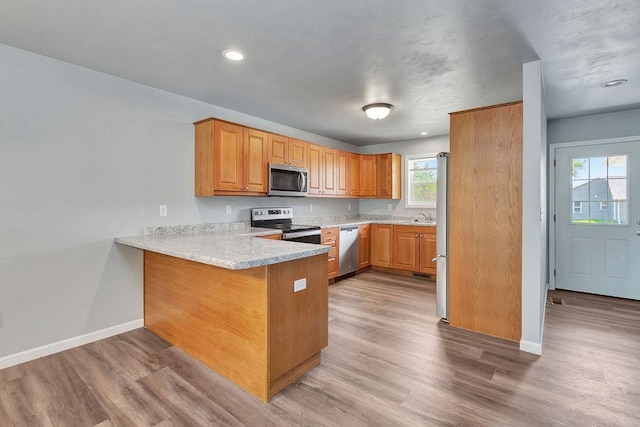 kitchen featuring light hardwood / wood-style floors, sink, kitchen peninsula, and stainless steel appliances