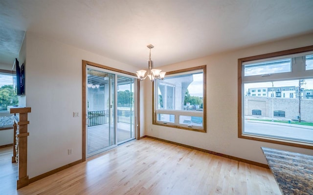 unfurnished dining area featuring an inviting chandelier and light hardwood / wood-style flooring