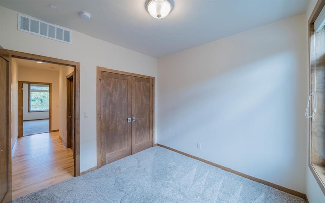 unfurnished bedroom with light carpet and a closet