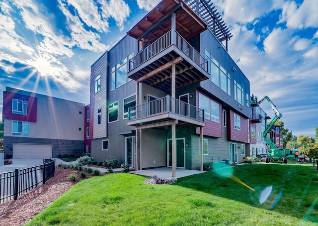 rear view of house featuring a patio, a balcony, and a lawn