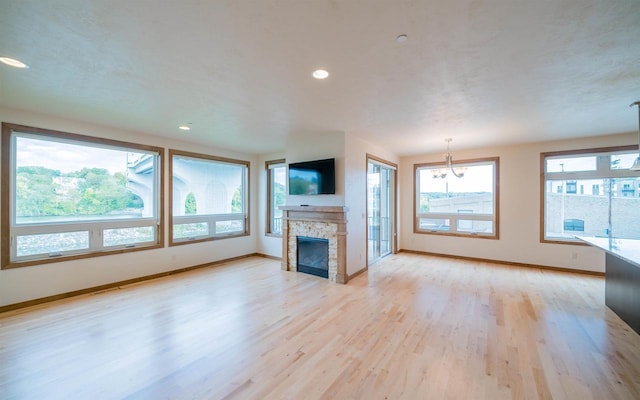 unfurnished living room featuring light wood-type flooring and a stone fireplace