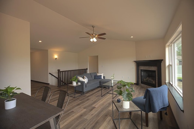 living room with a tile fireplace, hardwood / wood-style floors, vaulted ceiling, and ceiling fan