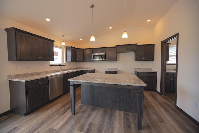 kitchen with a center island, sink, hanging light fixtures, vaulted ceiling, and stainless steel appliances