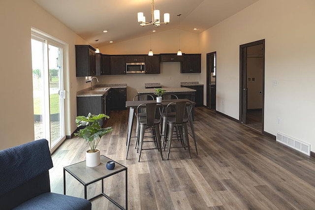 dining room with sink, wood-type flooring, lofted ceiling, and a notable chandelier