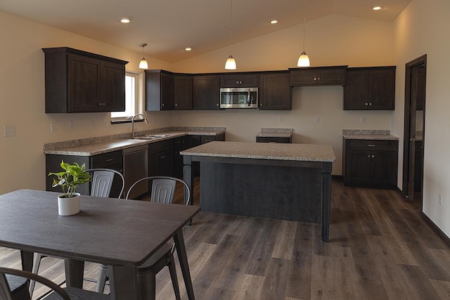 kitchen with appliances with stainless steel finishes, dark brown cabinetry, vaulted ceiling, a center island, and hanging light fixtures