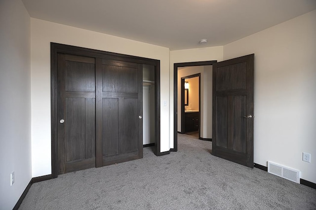 unfurnished bedroom with light colored carpet and a closet