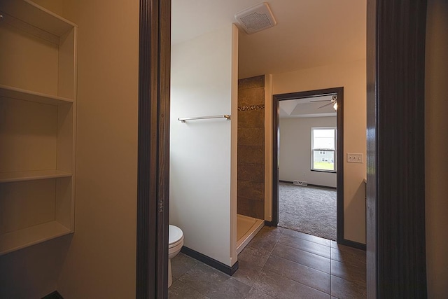 bathroom with tile patterned flooring, ceiling fan, toilet, and walk in shower