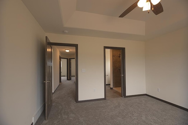 unfurnished bedroom with a raised ceiling, dark carpet, and ceiling fan