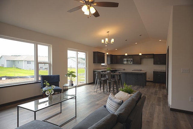 living room with ceiling fan with notable chandelier, dark hardwood / wood-style floors, and vaulted ceiling