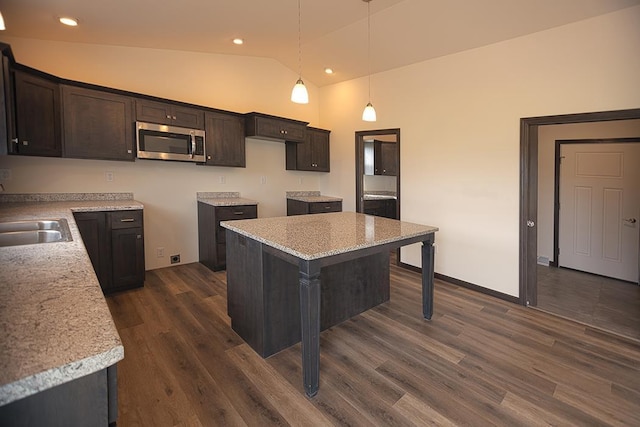 kitchen with pendant lighting, a center island, lofted ceiling, dark hardwood / wood-style flooring, and dark brown cabinetry