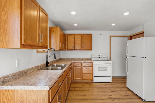 kitchen featuring brown cabinets, light countertops, a sink, light wood-type flooring, and white appliances