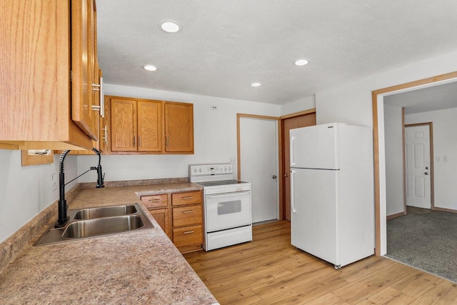 kitchen with white appliances, light countertops, light wood-type flooring, a sink, and recessed lighting