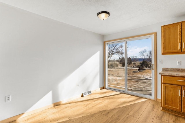 dining room with baseboards, visible vents, a textured ceiling, and light wood finished floors