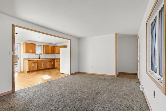 unfurnished living room featuring light carpet, baseboards, a sink, and recessed lighting