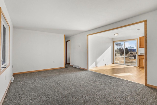 spare room featuring baseboards, visible vents, and light colored carpet